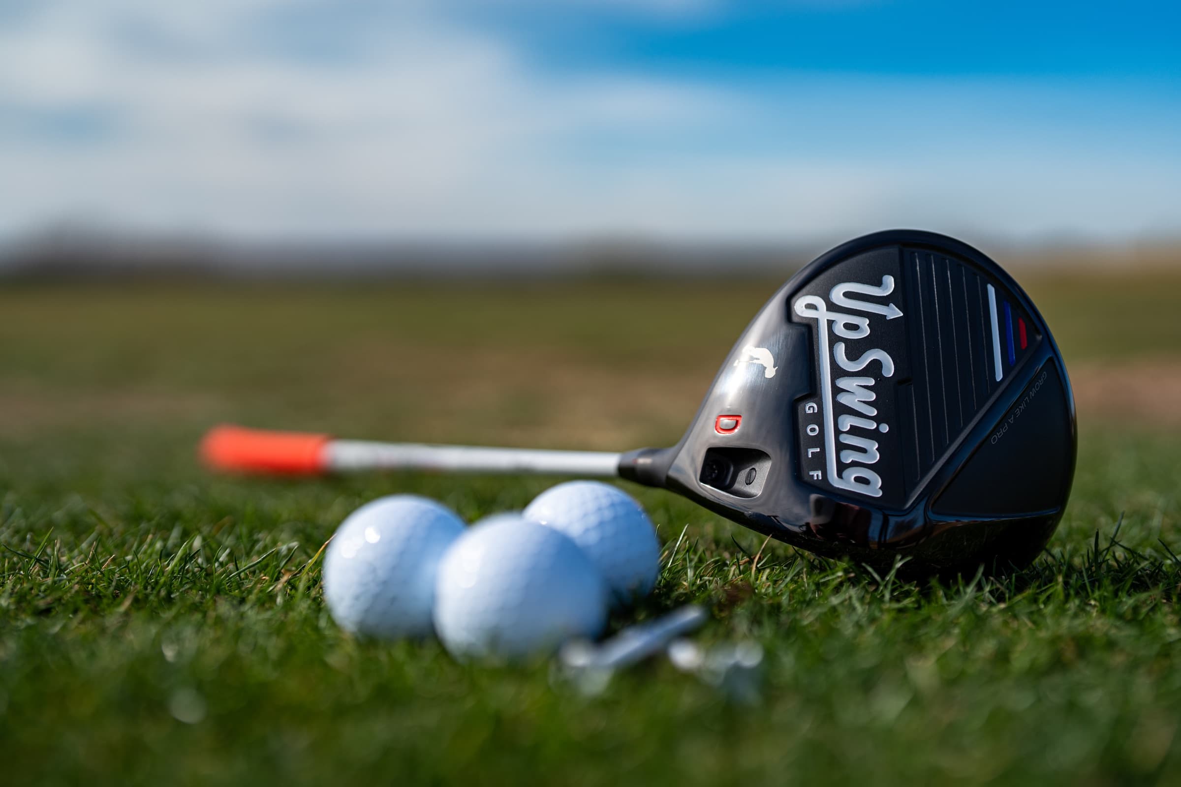 UpSwing Golf junior driver and golf balls on a course